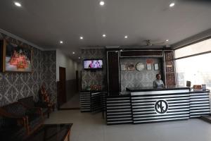 Un hombre de pie en una barra de un restaurante. en Hotel Neelkanth Katra, en Katra