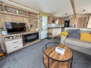 a living room with a couch and a tv and a table at Beautiful Caravan With Full Sea View At Broadland Sands In Suffolk Ref 20100Bs in Hopton on Sea