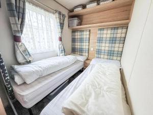 two beds in a small room with a window at Beautiful Caravan With Full Sea View At Broadland Sands In Suffolk Ref 20100Bs in Hopton on Sea