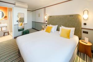 a hotel room with a large bed with yellow pillows at Best Western Plus Au Grand Saint Jean in Beaune