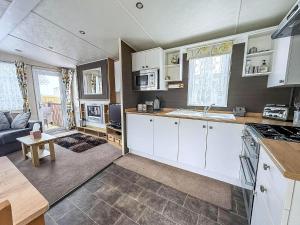 a kitchen with white cabinets and a living room at Brilliant Caravan With A Partial Sea View In Suffolk Ref 32026Az in Lowestoft +11 photos