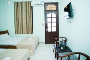 a hotel room with a bed and a tv and a door at Khách Sạn Mai Hà Sầm Sơn in Sầm Sơn
