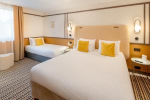 a hotel room with a large bed with yellow pillows at Best Western Plus Au Grand Saint Jean in Beaune