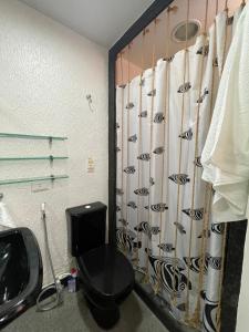 a bathroom with a black toilet and a shower curtain at CONDOMÍNIO IMPERIAL, PRAIA DO FRANCÊS in Praia do Frances +43 photos