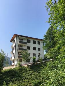 ein weißes Gebäude mit Bäumen davor in der Unterkunft Defne Apart in Çamlıhemşin