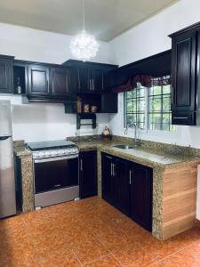 a kitchen with black cabinets and a sink and a stove at Casa de Wen in Santa Rita