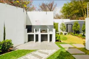 a white house with a fireplace in a yard at Stunning 1 bed in Midrand at 93 On New Estate in Midrand