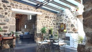 a room with a table and chairs in a stone wall at Le Pas Sage au Trible, Suites Bambou/ La Source/ Tataouine in Gluiras