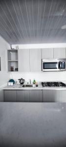 a white kitchen with a sink and a microwave at Apartamento en el centro de Matagalpa in Matagalpa