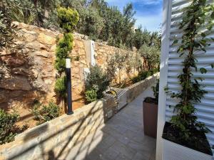 a garden with a stone wall and a pathway at VFH Residence Flavia -Tre Piscine in Santa Flavia