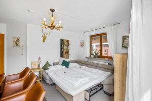a bedroom with a bed and a couch and a chandelier at CASARiNA - Alpentraum am Barmsee - FeWo Lugge in Krün