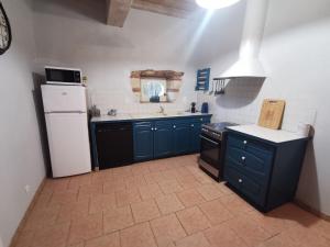 a kitchen with blue cabinets and a white refrigerator at La chacunière de Labarthe in Fleurance