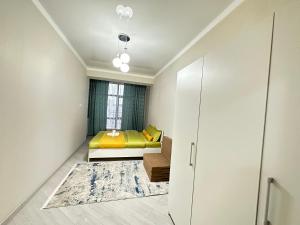 a bedroom with a yellow bed and a window at Etno Naz in Bishkek