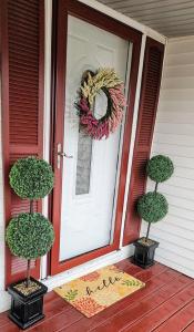 eine Haustür mit zwei Topfbäumen und einem Kranz in der Unterkunft Soak n Stroll 2 State St Casino Firepit Dogs OK in Bristol