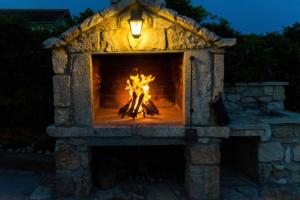 a fire in a stone fireplace at night at Ferienhaus In Posedarje Mit Großem Garten in Posedarje