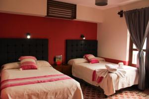 瓦哈卡市Lidia Anturios Suites的红色墙壁客房的两张床