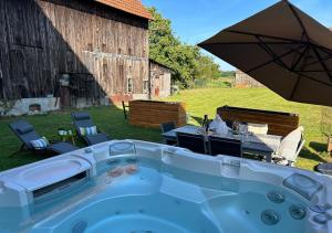 a hot tub with a table and an umbrella at Charmant Cottage de village in Wittisheim