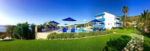 Kanakis Blue Beach Apartments في Petres: منتجع فيه مسبح ومظلات زرقاء