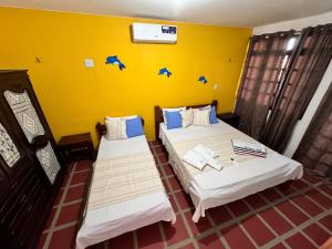 two beds in a room with a yellow wall at Splendide villa à morro branco vue sur mer in Beberibe +35 photos