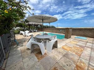 a patio with a table and chairs and an umbrella at Splendide villa à morro branco vue sur mer in Beberibe