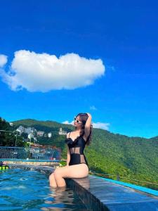 a woman in a bikini sitting in the water at BUNGALOW 2 -phòng săn mây vạn người mê in Tam Ðảo