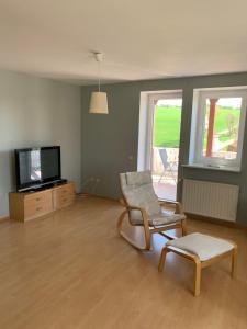 un soggiorno con sedia e TV di Preiswerte Ferienwohnung a Neukirchen