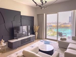 a living room with a tv and a large window at GRANDE RESIDENCES with a direct Burj Khalifa view and Private Fountain Show at 14th floor with DXB AIRPORT VIP Shuttle in Dubai