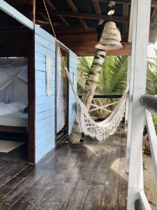 a hammock on the porch of a house with a palm tree at Hostal Paraíso & Vibra Restobar in Guachaca