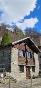a stone house with a roof on top of it at Boutique B&B La Quiete del Bosco - A Plant-Based Stay in Mesocco