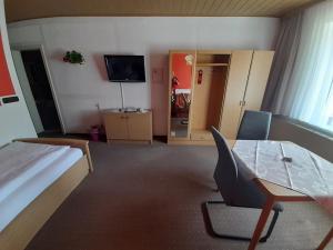a bedroom with a bed and a table and a television at Hotel Am Stadtwall in Anklam