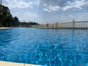 a pool of blue water in front of a white fence at Private Room Shared Apartment Sea View Pool Marbella Mijas in Sitio de Calahonda