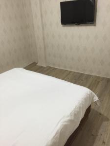 台北的住宿－嘉荣青年旅舍，配有一台平面电视的客房内的一张白色床