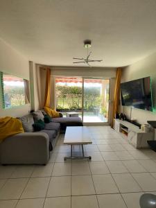 a living room with a couch and a table at 2P jardin Sud vue Lac avec piscine tennis parking privé in Le Cannet +2 photos