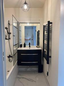a bathroom with a sink and a large mirror at 2P jardin Sud vue Lac avec piscine tennis parking privé in Le Cannet