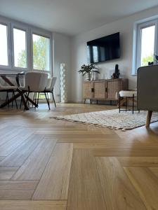 a living room with wooden floors and a tv on a wall at Studio 77 - nowoczesny apartament w Otwocku in Otwock