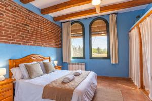 a bedroom with a bed with blue walls and windows at Can Pujol - Casitas de Turismo Rural en el Baix Empordà in Serra de Daró