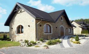 a stone house with a black roof at Noclegi Siwy Las in Oleszyce