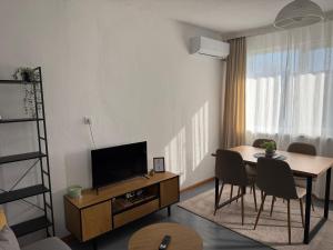 a living room with a television and a table and chairs at Апартамент за нощувки "Златен век" in Veliki Preslav
