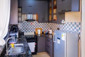 a kitchen with gray cabinets and a refrigerator at The Cozy Nest in Kampala