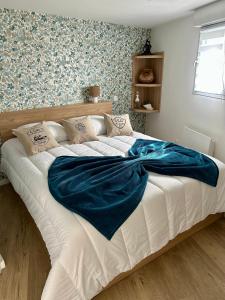 a large bed with a blue blanket on top of it at L'escapade d'émeraude in Saint-Cast-le-Guildo