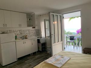 a kitchen with white cabinets and a door leading to a patio at Vila Pogled in Petrovac na Moru