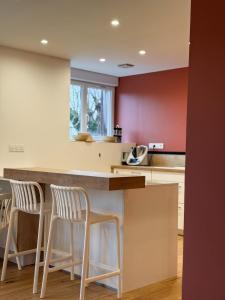 a kitchen with white stools and red walls at Casa Escuela in Plougastel-Daoulas +9 photos