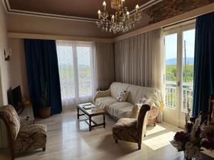a living room with a couch and chairs and a chandelier at Lidas Golden View-All around veranda apartment in Nafplio