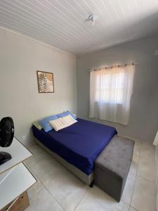une chambre avec un lit bleu et une fenêtre dans l'établissement Casa Azul, à 50m da Praia, Ilha dos Frades - Ponta de Nossa Senhora, à Salvador