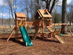 a wooden playground with a slide and a play structure at Sister Lakes Glamping Cabin at Wonder Woods #1 in Dowagiac