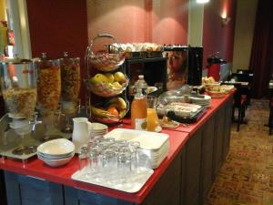 ein Buffet mit Tellern und Schüsseln voller Essen in der Unterkunft Hôtel Carmin in Le Havre