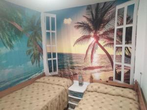 1 Schlafzimmer mit 2 Betten und einem Palmenmilch in der Unterkunft 3 Bed House Sleeps 6 with Pet-Friendly Garden in Corme-Puerto