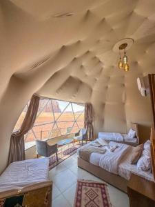 a room with two beds and a large window at Crimson wadi rum luxury in Wadi Rum +18 photos
