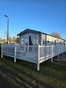塞顿港Silver 3 Bed Static Caravan With Patio的移动房屋设有门廊和白色围栏
