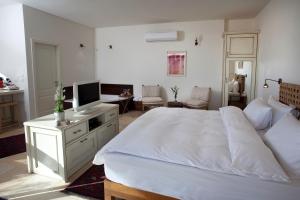 a bedroom with a large white bed and a television at Boutique Hotel Tamarin in Rosh Pinna